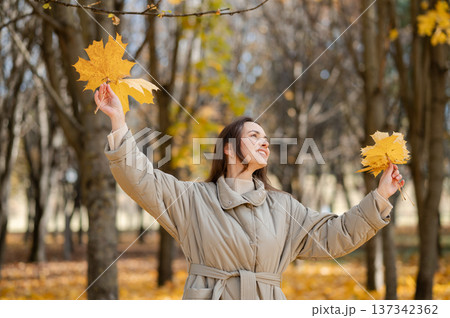 Happy woman with yellow autumn leaves enjoying fall day in sunny park with golden trees Happy woman with yellow autumn leaves enjoying fall day in sunny park with golden trees 137342362