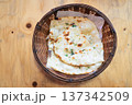 Top view of freshly baked garlic naan bread served in a wicker basket on a wooden table 137342509
