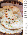 Close-up of freshly baked garlic naan bread served in a wicker basket on a wooden table 137342510