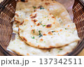 Close-up of freshly baked garlic naan bread served in a wicker basket on a wooden table 137342511