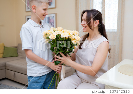 Teenage boy giving mother a bouquet of yellow roses for Mother's Day or International Women's Day Teenage boy giving mother a bouquet of yellow roses for Mother's Day or International Women's Day 137342536