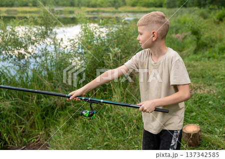 Teenage boy learning to cast fishing rod on lake shore, enjoying outdoor summer activity Teenage boy learning to cast fishing rod on lake shore, enjoying outdoor summer activity 137342585