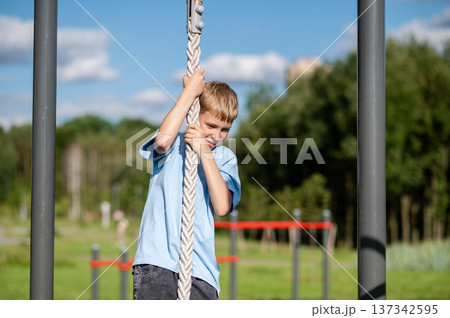 Teen boy training on rope at outdoor sports ground Teen boy training on rope at outdoor sports ground 137342595