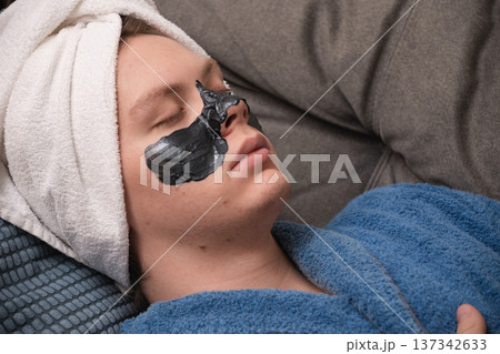 Man resting with black face mask. Mens Home Self-Care Routine Man resting with black face mask. Mens Home Self-Care Routine 137342633