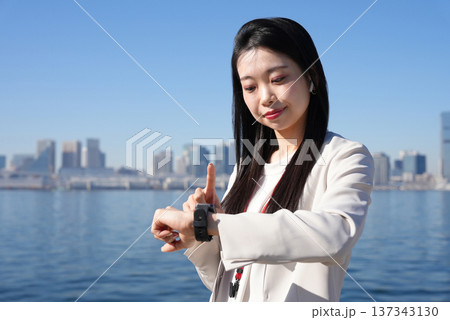スマートウォッチを見る若いビジネスウーマン スマートウォッチを見る若いビジネスウーマン 137343130