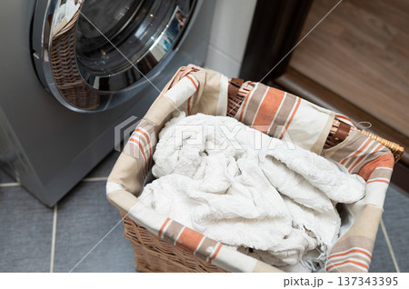 Laundry basket with dirty clothes next to washing machine in bathroom Laundry basket with dirty clothes next to washing machine in bathroom 137343395