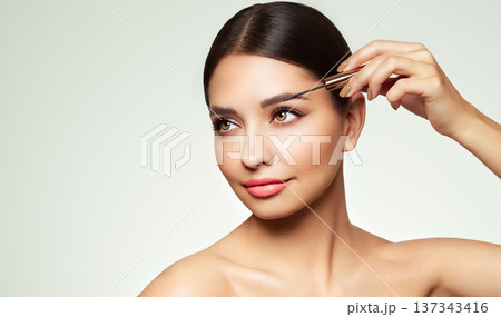 Beautiful woman puts mascara on her eyebrows 137343416