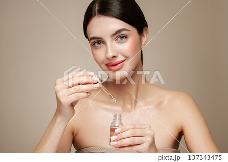 Young beautiful woman applying face serum Young beautiful woman applying face serum 137343475