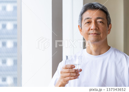 窓辺で水を飲むシニア男性 窓辺で水を飲むシニア男性 137343652