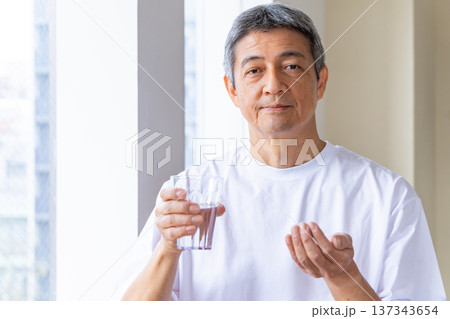 窓辺で薬を飲むシニア男性 137343654