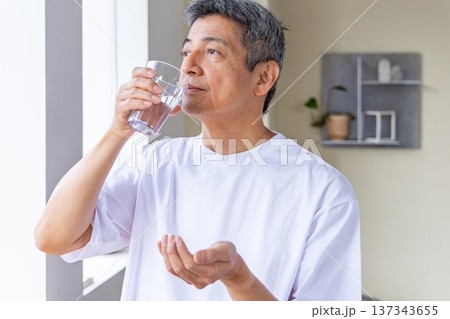 窓辺で薬を飲むシニア男性 137343655
