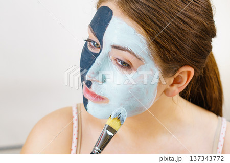 Girl black mask on half face apply white mud Girl black mask on half face apply white mud 137343772