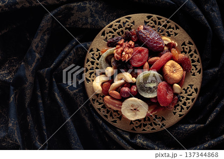 Dried tropical fruits and nuts in a golden bowl. Dried tropical fruits and nuts in a golden bowl. 137344868