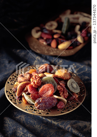 Dried tropical fruits and nuts in a golden bowl. Dried tropical fruits and nuts in a golden bowl. 137344870