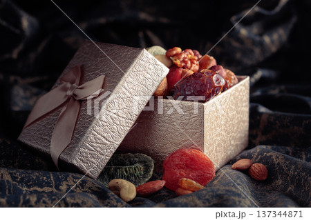 Dried tropical fruits, nuts, and raisins in gift box. 137344871