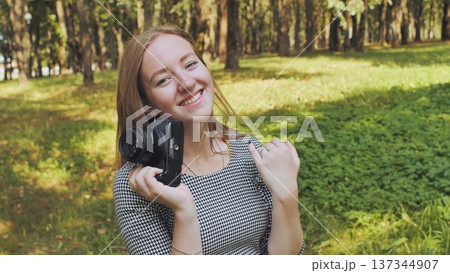 Professional photographer grinning, gripping camera amid lush greenery under bright sunlight Professional photographer grinning, gripping camera amid lush greenery under bright sunlight 137344907