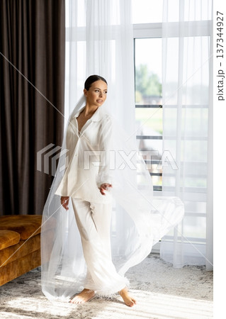 Bride wearing white pajamas and veil getting ready for wedding ceremony Bride wearing white pajamas and veil getting ready for wedding ceremony 137344927