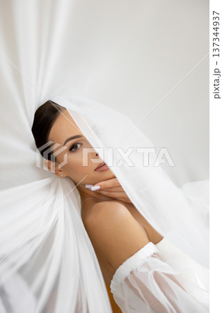 Bride holding veil looking away in wedding dress 137344937