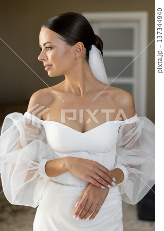Bride wearing white wedding dress with puffy sleeves posing indoors Bride wearing white wedding dress with puffy sleeves posing indoors 137344940