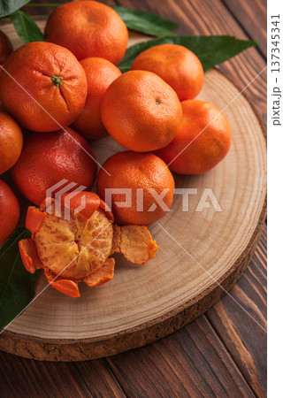 Fresh Tangerines with Leaves on Rustic Wooden Slab 137345341