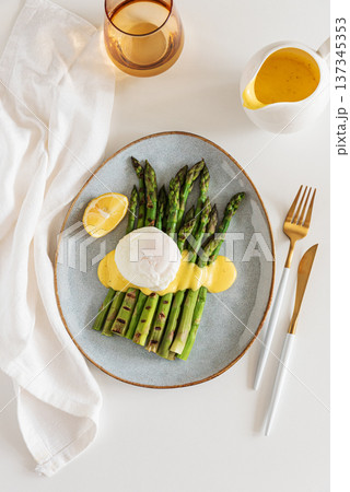 Grilled asparagus spears topped with poached egg and hollandaise sauce, garnished with fresh lemon wedge Grilled asparagus spears topped with poached egg and hollandaise sauce, garnished with fresh lemon wedge 137345353