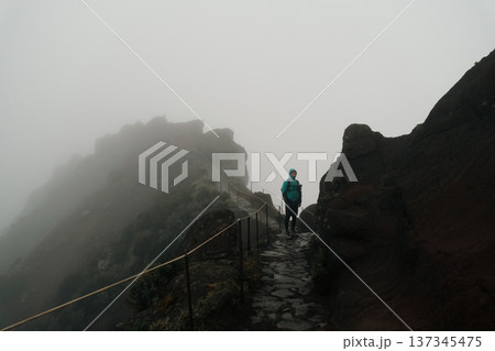 An individual confidently traverses cloudcovered mountain ridge 137345475