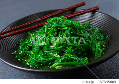 Chuka salad, made from fresh seaweed, with sesame dressing, served in a black bowl, with chopsticks, 137345669