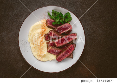 Sliced steak, served with creamy mashed potatoes, and fresh herbs, no people Sliced steak, served with creamy mashed potatoes, and fresh herbs, no people 137345671