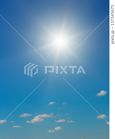 Bright Sun Shining in a Clear Blue Sky with Fluffy White Clouds 137345675