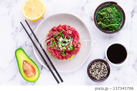 Fresh tuna tartare with avocado served on a marble table with soy sauce and seaweed salad Fresh tuna tartare with avocado served on a marble table with soy sauce and seaweed salad 137345706