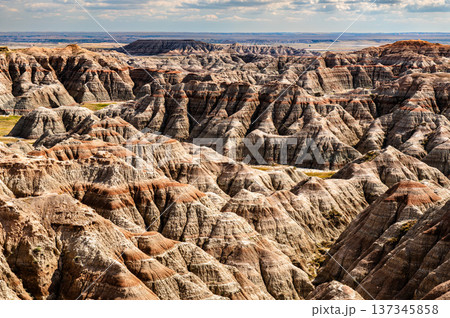 Scenic sunny view of the rugged and colorful eroded rock formations from Burns Basin Overlook in Badlands National Park, South Dakota, United States. Scenic sunny view of the rugged and colorful eroded rock formations from Burns Basin Overlook in Badlands National Park, South Dakota, United States. 137345858