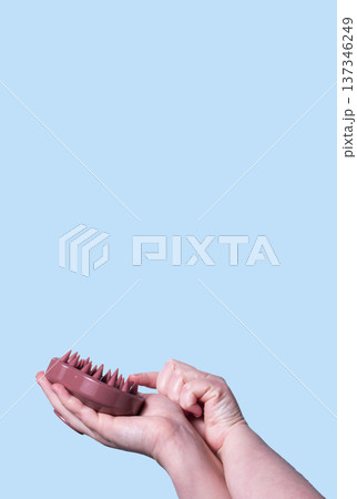 Hair brush for stimulating hair growth on blue background. Microcirculation, help to distribute natural oils more evenly across the scalp Hair brush for stimulating hair growth on blue background. Microcirculation, help to distribute natural oils more evenly across the scalp 137346249