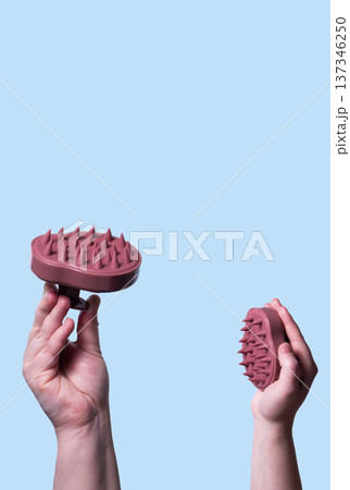 Hair pink scalp massager in woman hand on the pink background isolated. Image with copy space. Mock up for design and banner Hair pink scalp massager in woman hand on the pink background isolated. Image with copy space. Mock up for design and banner 137346250