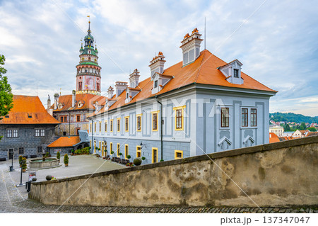 Visitors explore the grounds of Cesky Krumlov Castle in summer. The castle features historic architecture and offers views of the surrounding area. People enjoy walking and taking photos. 137347047