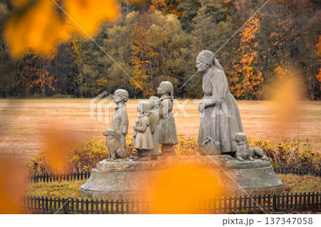 In Granny Valley, Ratiborice, Czechia, a statue depicts a loving grandmother and her grandchildren amidst vibrant autumn leaves. This memorial honors the writer Bozena Nemcova. 137347058