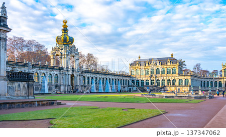 Visitors explore the Zwinger Palace in Dresden, Germany. This historic site features gardens and galleries. Christmas decorations enhance the beauty of the Baroque architecture in winter. 137347062