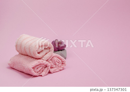 Pink fluffy towels folded neatly on a grey surface, ideal for mockups with room for your design or message. Pink fluffy towels folded neatly on a grey surface, ideal for mockups with room for your design or message. 137347301
