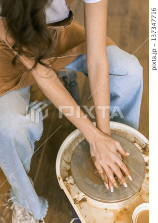 Young woman shaping clay on pottery wheel in ceramic workshop, handmade pottery process and creative craft activity in studio 137347716