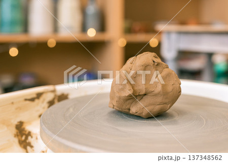 Close up of female hands shaping clay on pottery wheel in ceramic studio, handmade pottery process and traditional craft 137348562