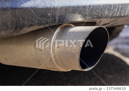 Close up of a car exhaust pipe with dirt buildup and shiny metal parts under clear sunlight on a roadway Close up of a car exhaust pipe with dirt buildup and shiny metal parts under clear sunlight on a roadway 137348610