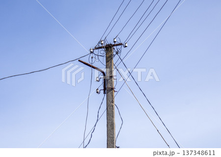An electric pole supports multiple wires against a clear blue sky during daylight hours, showcasing utility infrastructure An electric pole supports multiple wires against a clear blue sky during daylight hours, showcasing utility infrastructure 137348611