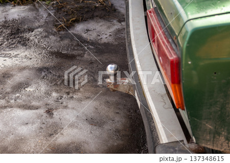A green car shows a towbar at the back while parked on icy ground in a rural area during winter 137348615