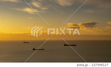 Cargo Ships At Sunset On Calm Ocean Horizon With Golden Sky And Tranquil Sea Vessels 137349127