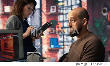 Coworkers using AI chatbot interface to generate video game spaceship environments, modern system applies deep learning and machine learning techniques. Developing sci fi gaming designs. Camera B. 137350520