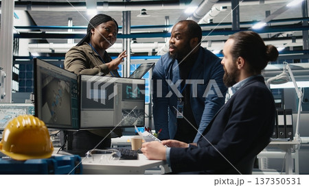 Multiethnic team of energy consultants review insight in solar panel plant, ensuring high standards in alternative energy production line. Quality control and manufacturing process. Camera A. 137350531