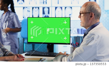 Experienced physician doing check up routine with patient next to chroma key screen, discussing about medicine and wellness. Old woman using health insurance for consultation with medic. Camera B. Experienced physician doing check up routine with patient next to chroma key screen, discussing about medicine and wellness. Old woman using health insurance for consultation with medic. Camera B. 137350553