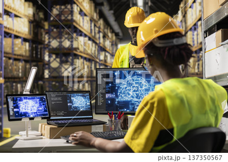 Black woman with hi vis vest and helmet uses artificial intelligence tools for automation and modern deep learning, using AI data mining for e-commerce order processing. Warehouse. Black woman with hi vis vest and helmet uses artificial intelligence tools for automation and modern deep learning, using AI data mining for e-commerce order processing. Warehouse. 137350567