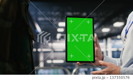 Military technicians in data center use green screen mockup tablet to monitor systems. Army operators in server room ensuring stable infrastructure using chroma key device 137350576