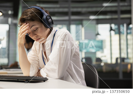 Tired programmer in Silicon Valley company office listening music to destress. Exhausted IT specialist wearing headphones closing eyes to relax at work while debugging applications Tired programmer in Silicon Valley company office listening music to destress. Exhausted IT specialist wearing headphones closing eyes to relax at work while debugging applications 137350650