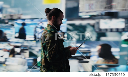 Army officer working in a virtual war zone with digital tech and satellite data, using threat detection tools for national safety. Modern military strategy to ensure control in a mission. Camera A. Army officer working in a virtual war zone with digital tech and satellite data, using threat detection tools for national safety. Modern military strategy to ensure control in a mission. Camera A. 137350660